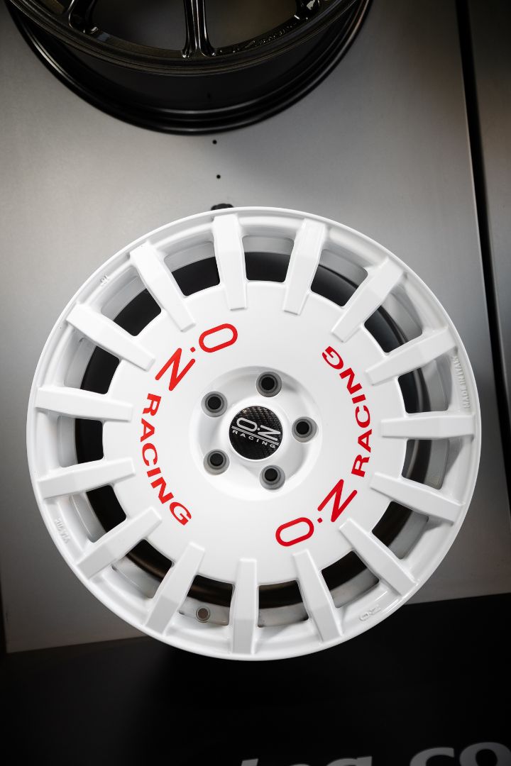 Cerchio OZ Racing bianco con scritte OZ RACING rosse stile rally su espositore