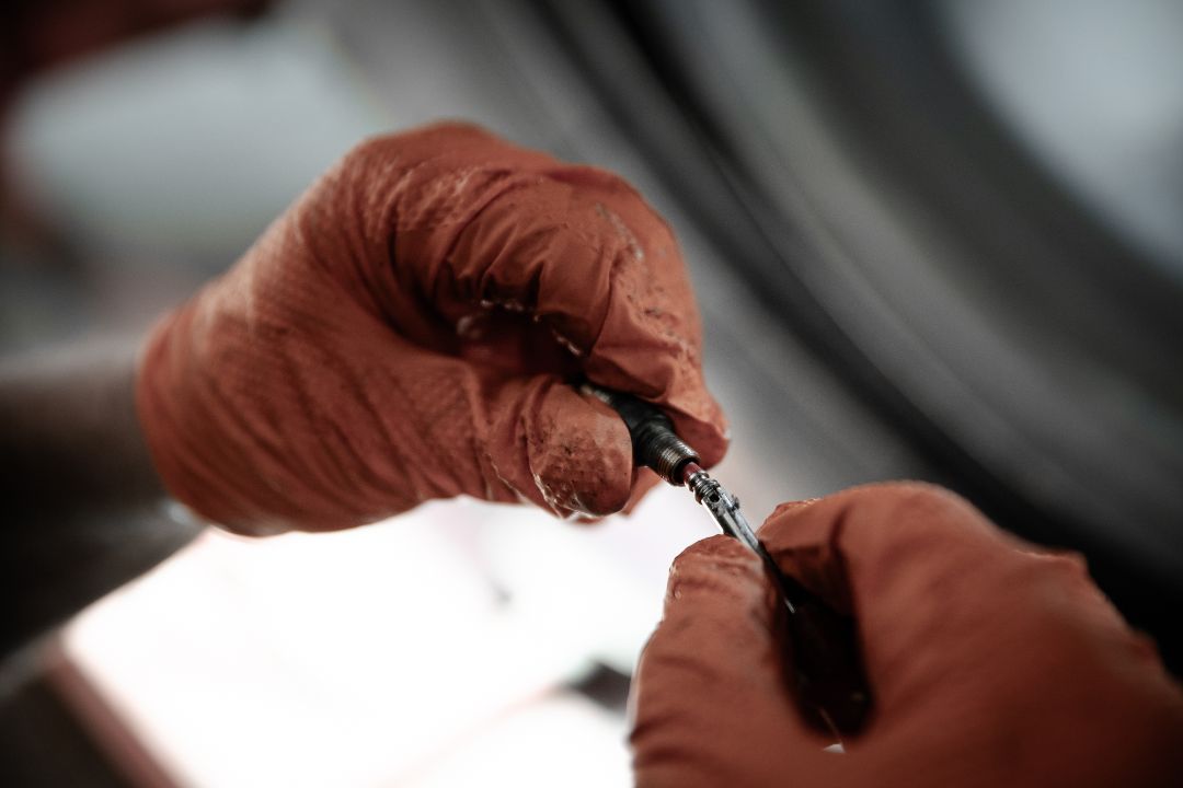 Dettaglio mani con guanti del tecnico Ermes Gomme durante riparazione