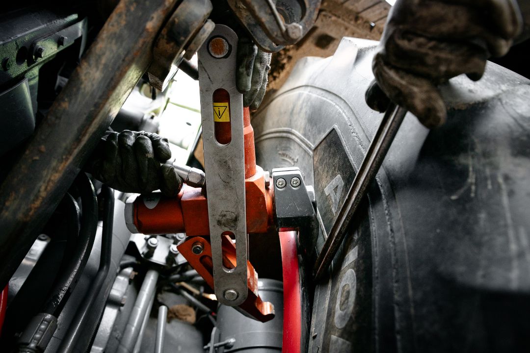 Tecnico Ermes Gomme usa cric idraulico per sollevare trattore durante sostituzione pneumatico agricolo